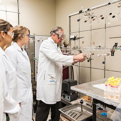 Group of students watching a professor's demonstration in the lab